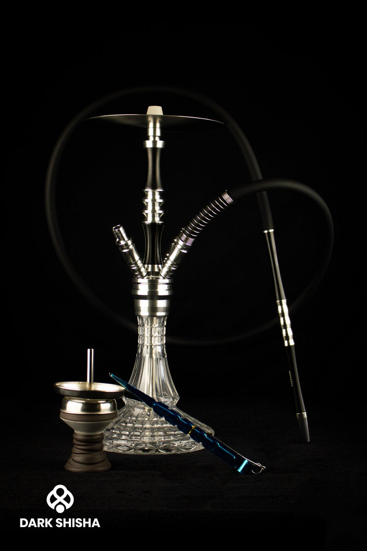 Narghilè Crystalia Elektra Shisha in nero e argento con ampolla in vetro grande e design elegante. Dotato di sistema a camera chiusa e quattro connettori per fumare fino a quattro persone contemporaneamente. Altezza di 52 cm senza testa.